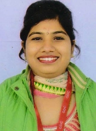 Portrait of Dr. Verma in traditional Indian attire standing in front of bookshelves